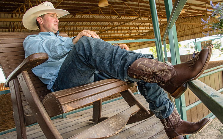 Man sitting in chair wearing a pair of brown Justin boots